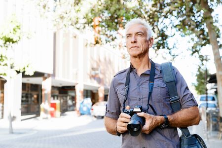 Senior man with camera in cityの写真素材