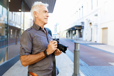 Senior man with camera in cityの写真素材