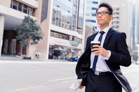 Businessman swalking in street and holding a coffeeの写真素材