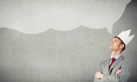 Young handsome businessman wearing white paper crownの写真素材