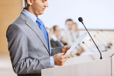 Businessman standing on stage and reporting for audienceの写真素材