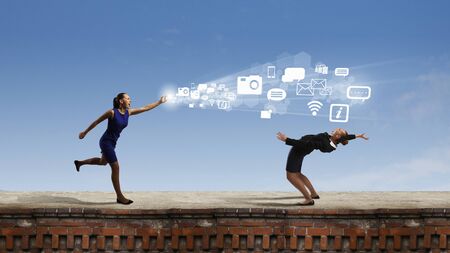 Young businesswoman benting back from flying iconsの写真素材