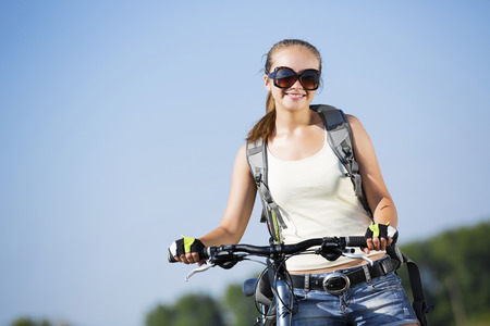 Young beautiful woman riding a bicycle in a parkの写真素材