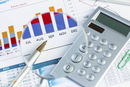 Magnifing glass and documents with analytics data lying on tableの写真素材