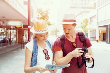 Happy young couple as tourists with a mapの写真素材