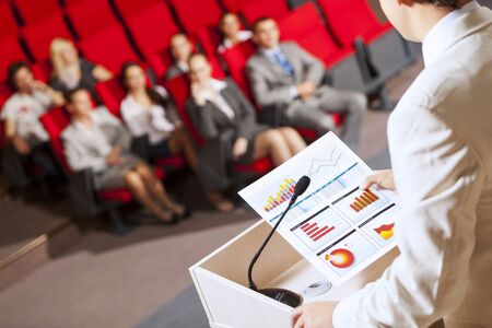 Businessman standing on stage and reporting for audienceの写真素材
