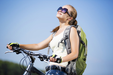 Young beautiful woman riding a bicycle in a parkの写真素材