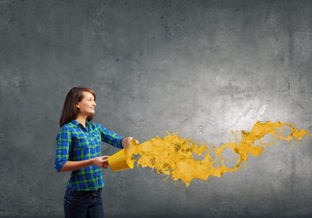 Young woman in casual holding yellow bucket with splashes