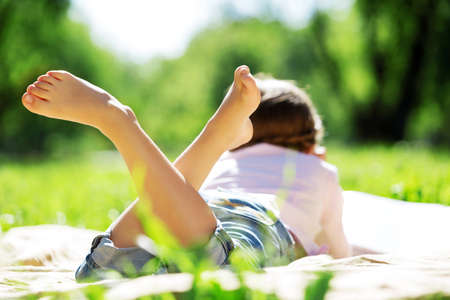 Child lying on blanket having picnic in summer parkの写真素材