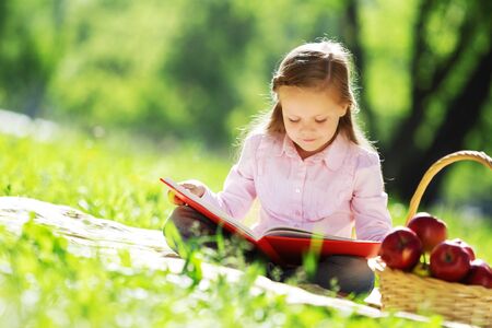 Child with book having picnic in summer parkの写真素材