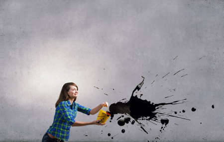 Young woman in casual holding yellow bucket with splashesの写真素材