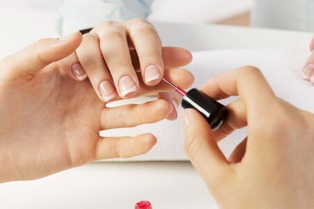 Woman in nail salon receiving manicure by beauticianの写真素材