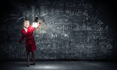 Young pretty businesswoman with lantern in darknessの写真素材