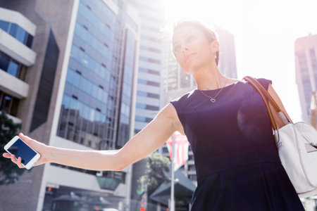 Businesswoman in a city street waving for taxi