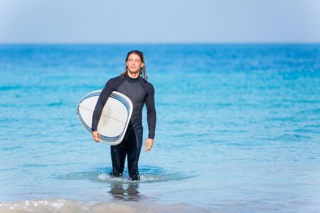 A young surfer with his board on the beachの写真素材