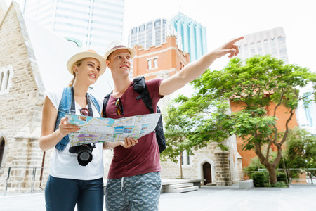 Happy young couple as tourists with a mapの写真素材