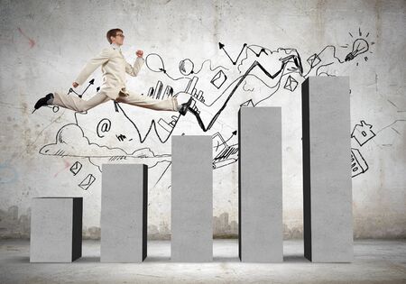 Young businessman stepping up on chart barの写真素材