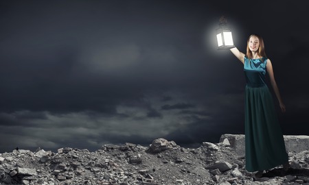 Young woman with lantern walking in darknessの写真素材