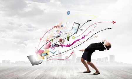 Young businesswoman evading colorful splashes flying from laptopの写真素材