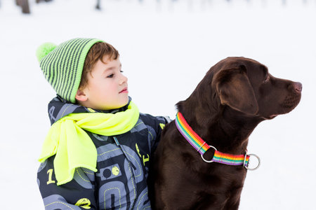 Kid of school age with dog in winter parkの写真素材