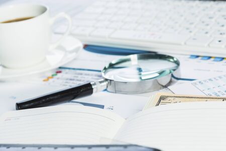 Magnifing glass and documents with analytics data lying on tableの写真素材