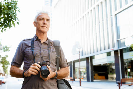 Senior man with camera in cityの写真素材