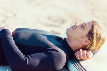 A young surfer with his board on the beachの写真素材