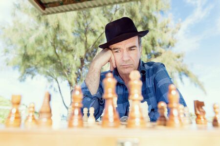 Elderly man sitting outdoors with chessの写真素材