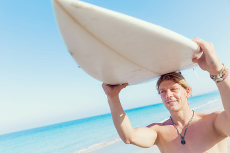 A young surfer with his board on the beach