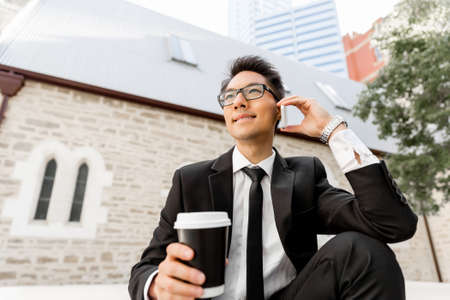 Businessman in city holding his mobileの写真素材
