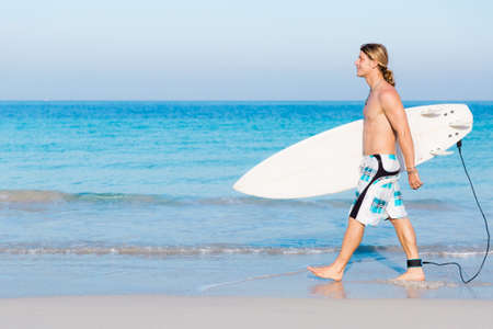 A young surfer with his board on the beachの写真素材