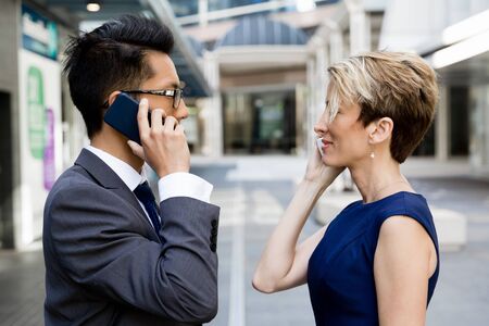 Business people standing in stret with their mobilesの写真素材