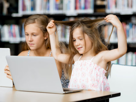 Little girls with a laptop in libraryの写真素材