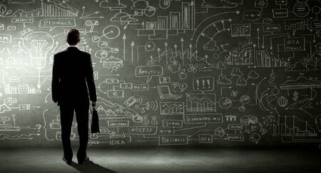 Rear view of businessman looking at business sketch on wallの写真素材