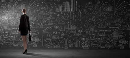 Rear view of businesswoman looking at business sketch on wallの写真素材