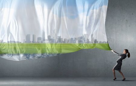 Young pretty businesswoman pulling clothing banner with illustrationの写真素材