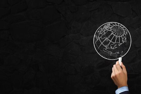 Close up of hand drawing globe on blackboardの写真素材