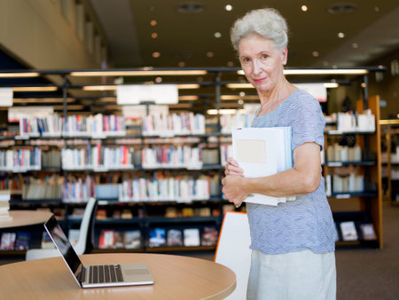 Elderly lady standing next to table with laptop