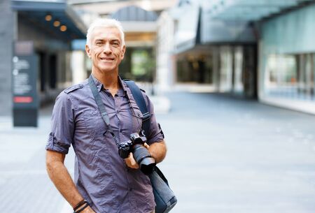 Senior man with camera in cityの写真素材