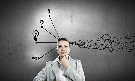 Young thoughtful businesswoman and thoughts coming out of her headの写真素材