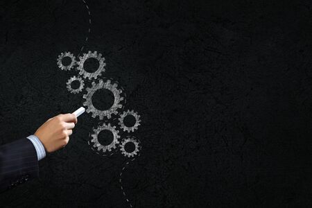 Close up of hand drawing gears mechanism with chalkの写真素材