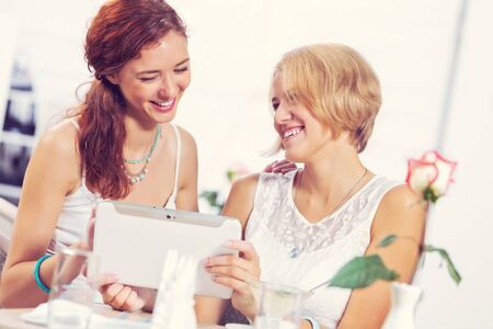 Two pretty female friends meeting in cafeの写真素材