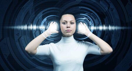 Young woman wearing headphones on digital blue backgroundの写真素材