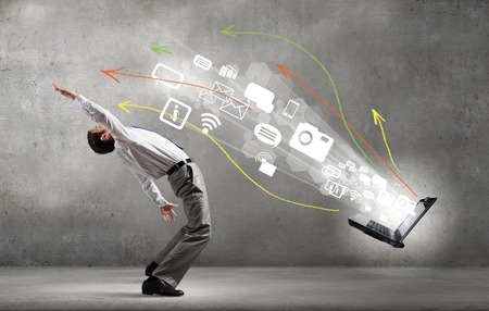 Young businessman evading icon flying from laptopの写真素材