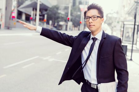 Businessman trying to catch a taxi in business cuty districtの写真素材