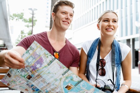 Happy young couple as tourists with a mapの写真素材