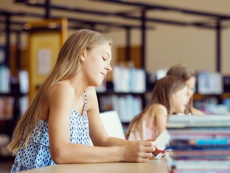 Little girls reading books in libraryの写真素材