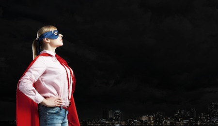 Young confident woman in red cape and maskの写真素材
