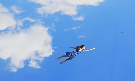 Happy young woman dreaming to fly in skyの写真素材
