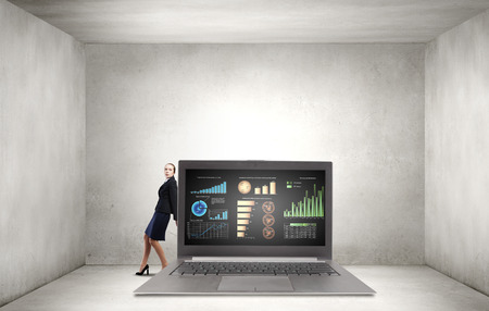 Young businesswoman making effort to move huge laptopの写真素材